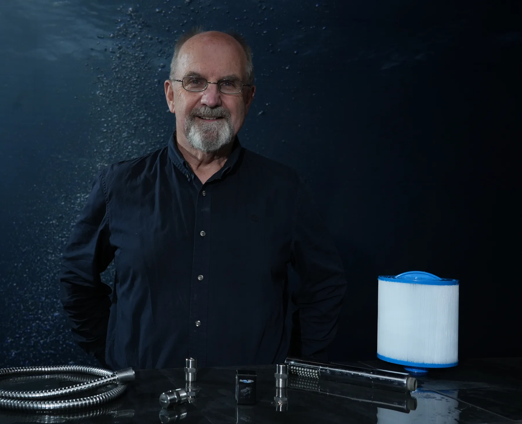 Arild Olsvik, founder of RinWaJet, at a workbench with a spa cartridge filter, shower hose and the RinWaJet nozzle
